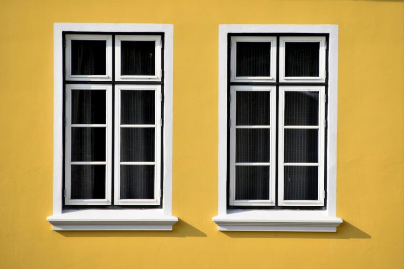 Biele drevené okná na žltom dome